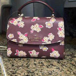 Kate Spade micro satchel in deep berry with floral accent.